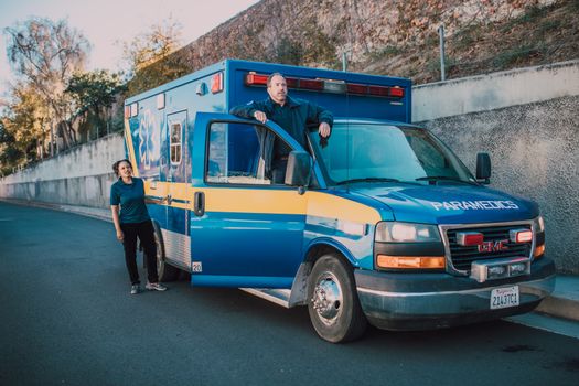 Ambulance with paramedics ready for an emergency response on a sunny day.