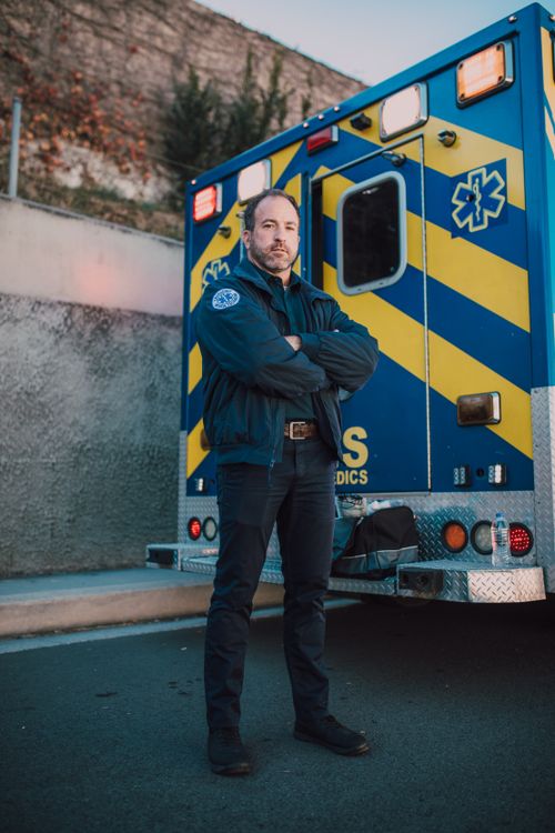 Free Confident paramedic standing next to an ambulance on a sunny day. Stock Photo