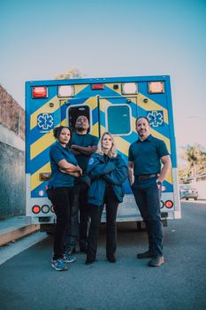 A team of paramedics confidently standing in front of their ambulance, ready for action.