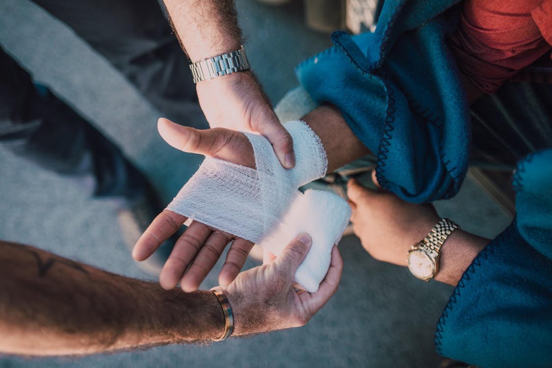 Free Person Applying Bandage on Another Person's Hand Stock Photo