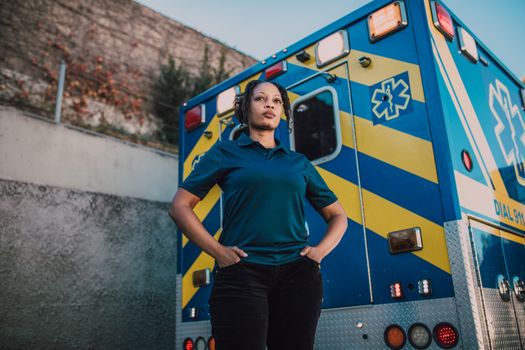 A strong paramedic standing confidently next to an ambulance outdoors, exuding professionalism and readiness.