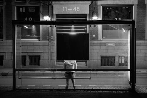 Grayscale Photography of Person Sitting on Shed