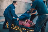 Paramedics assisting a patient on a stretcher outdoors, emphasizing teamwork and care.