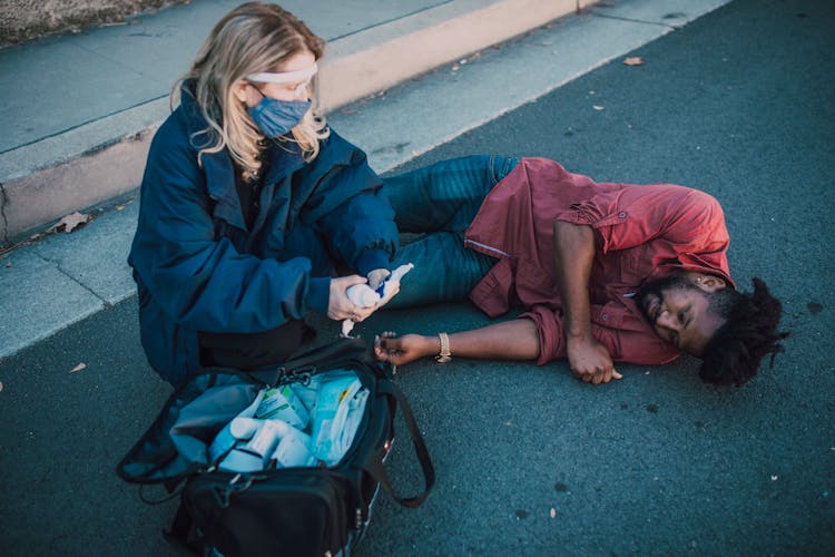 Paramedic Helping A Man Lying On The Ground