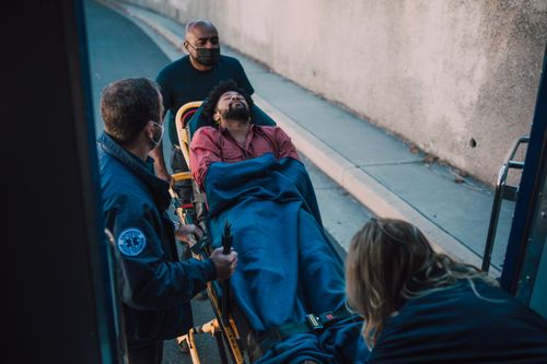 Free Paramedics assist a patient on a stretcher during an emergency response. Outdoors setting. Stock Photo
