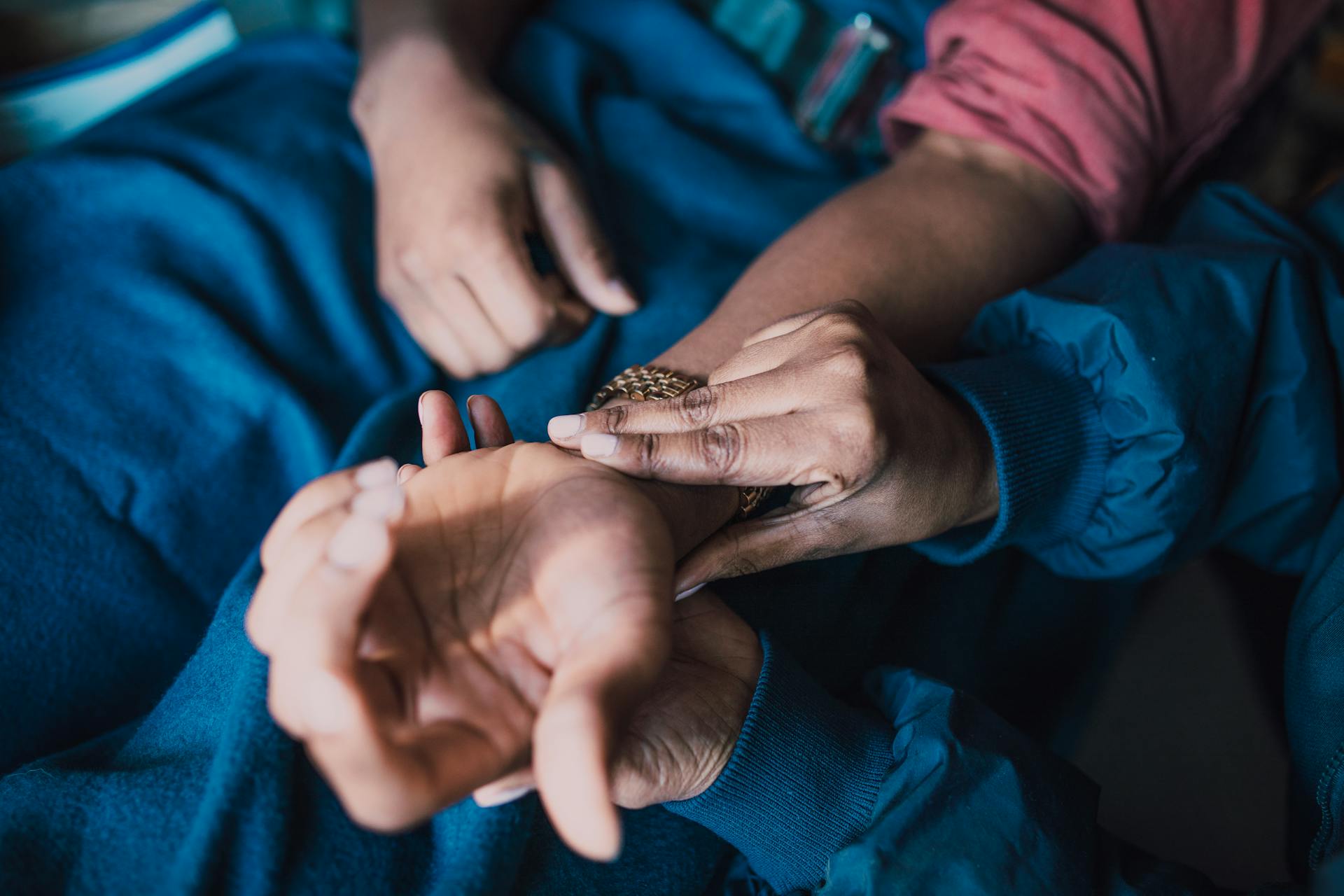 Close-up of hands checking a pulse on a patient's wrist, illustrating healthcare and care.