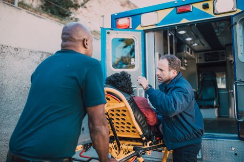 Free First responders assisting a patient into an ambulance for medical aid. Stock Photo