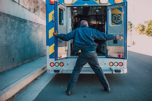 Emergency responder loads an ambulance on a city street, readying for action.