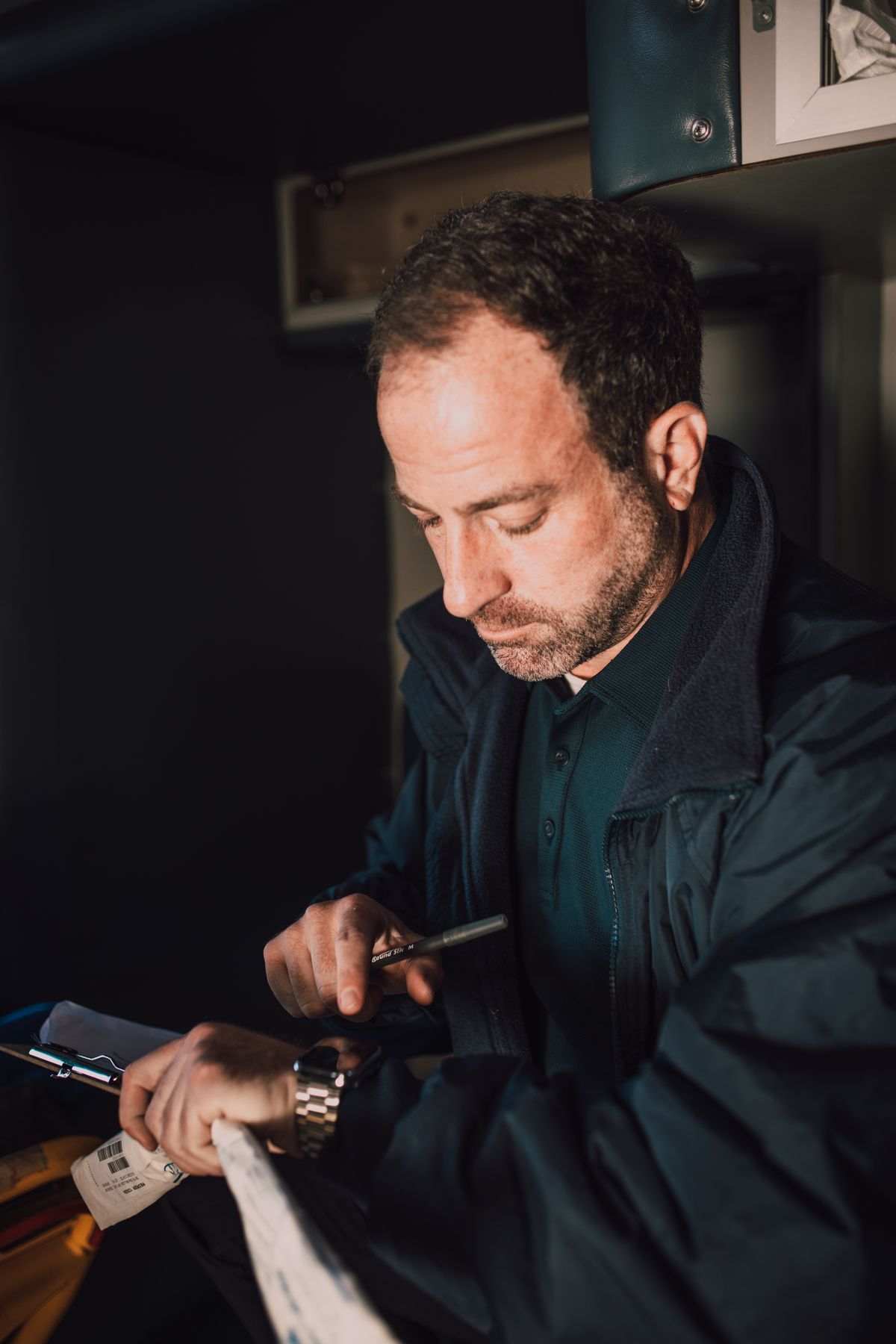 Paramedic checking the time while holding medical notes