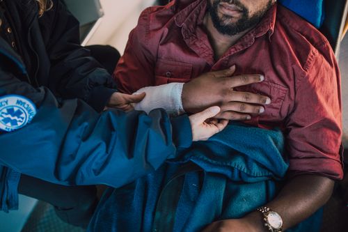 Free Paramedic assisting injured patient with arm bandaged in an emergency scenario. Stock Photo