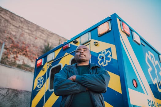 Paramedic stands confidently with arms crossed in front of an ambulance.