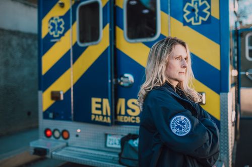 Free Confident paramedic with folded arms in front of an ambulance, showcasing dedication and professionalism. Stock Photo