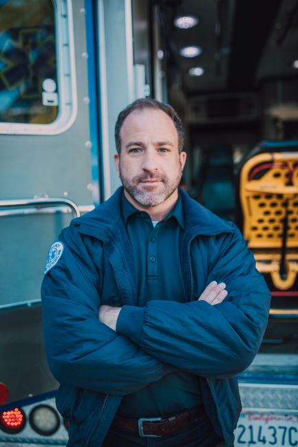 Portrait of a paramedic standing confidently with arms crossed by an ambulance.