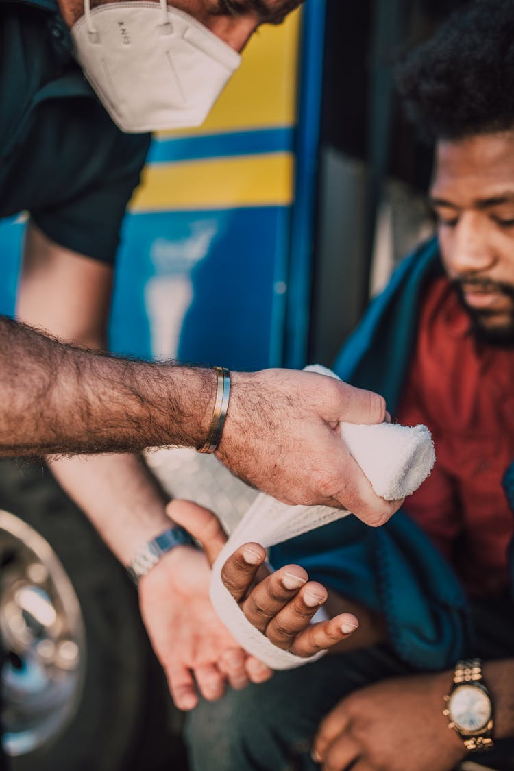 Paramedic Putting Bandage On Man's Hand