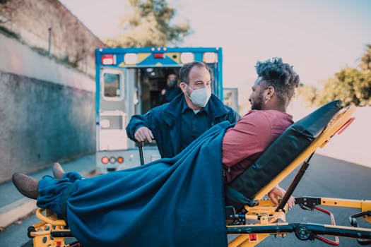 A paramedic aids a man on a stretcher near an ambulance outdoors.