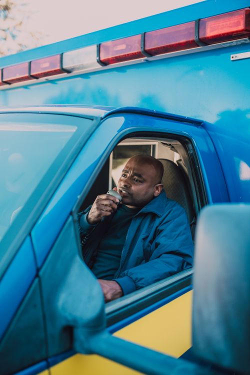 Free A paramedic in an ambulance talking on a radio, ready to respond to an emergency. Stock Photo
