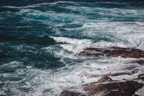 Free Vibrant ocean waves crash against rocky shoreline, creating dramatic splashes and dynamic motion. Stock Photo