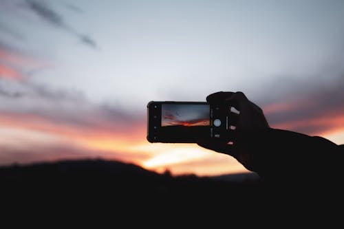 Person Holding a Smartphone Taking Photo of Sunset