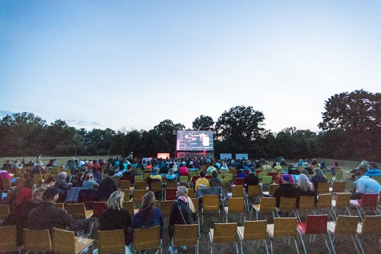 People Sitting On Chairs In An Outdoor Cinema 