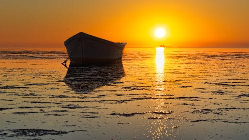 Free Silhouette of a Boat on the Beach during Sunset Stock Photo