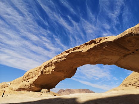 Stunning natural rock arch in Jordan under a clear blue sky, perfect for nature enthusiasts.