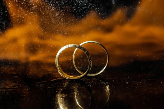 Stunning close-up of two gold wedding rings against a dramatic backdrop. Perfect for wedding and romance themes.