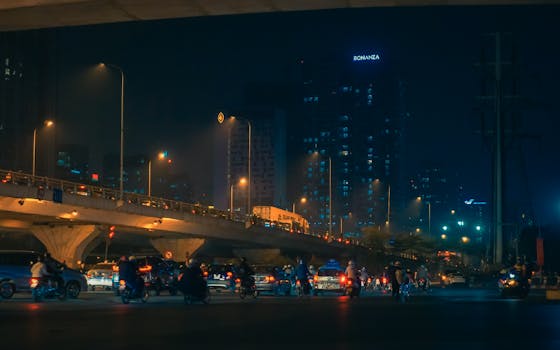 Street view of night traffic under citylights in Hà Nội, showcasing urban life.