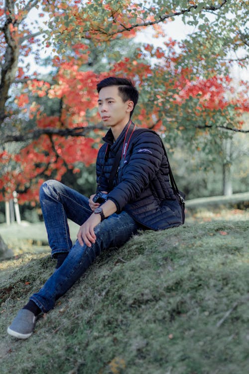 Man in Black Bubble Jacket sitting on Grass