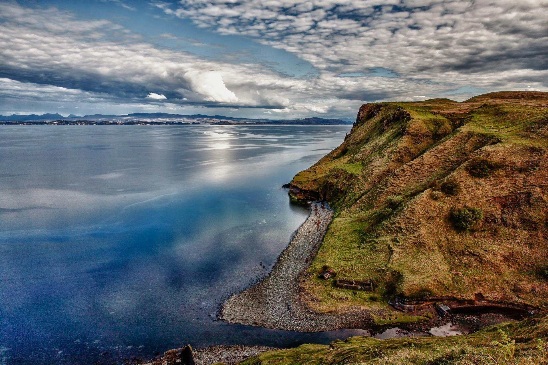 Stunning coastal view featuring dramatic cliffs and a calm sea under a cloudy sky.