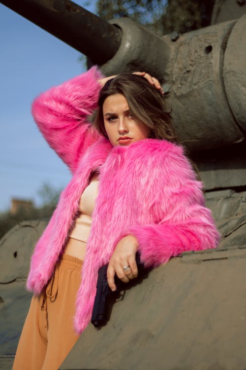 A Woman in a Pink Fur Coat Holding a Pistol