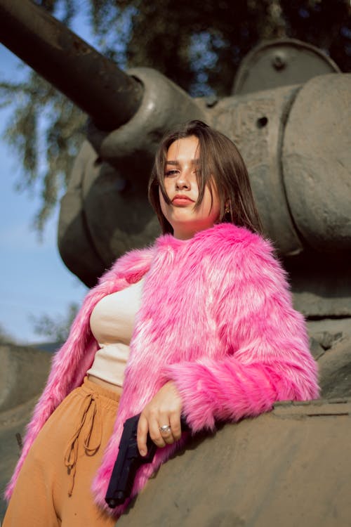 A Pretty Woman in Pink Fur Coat Leaning on a Concrete Structure