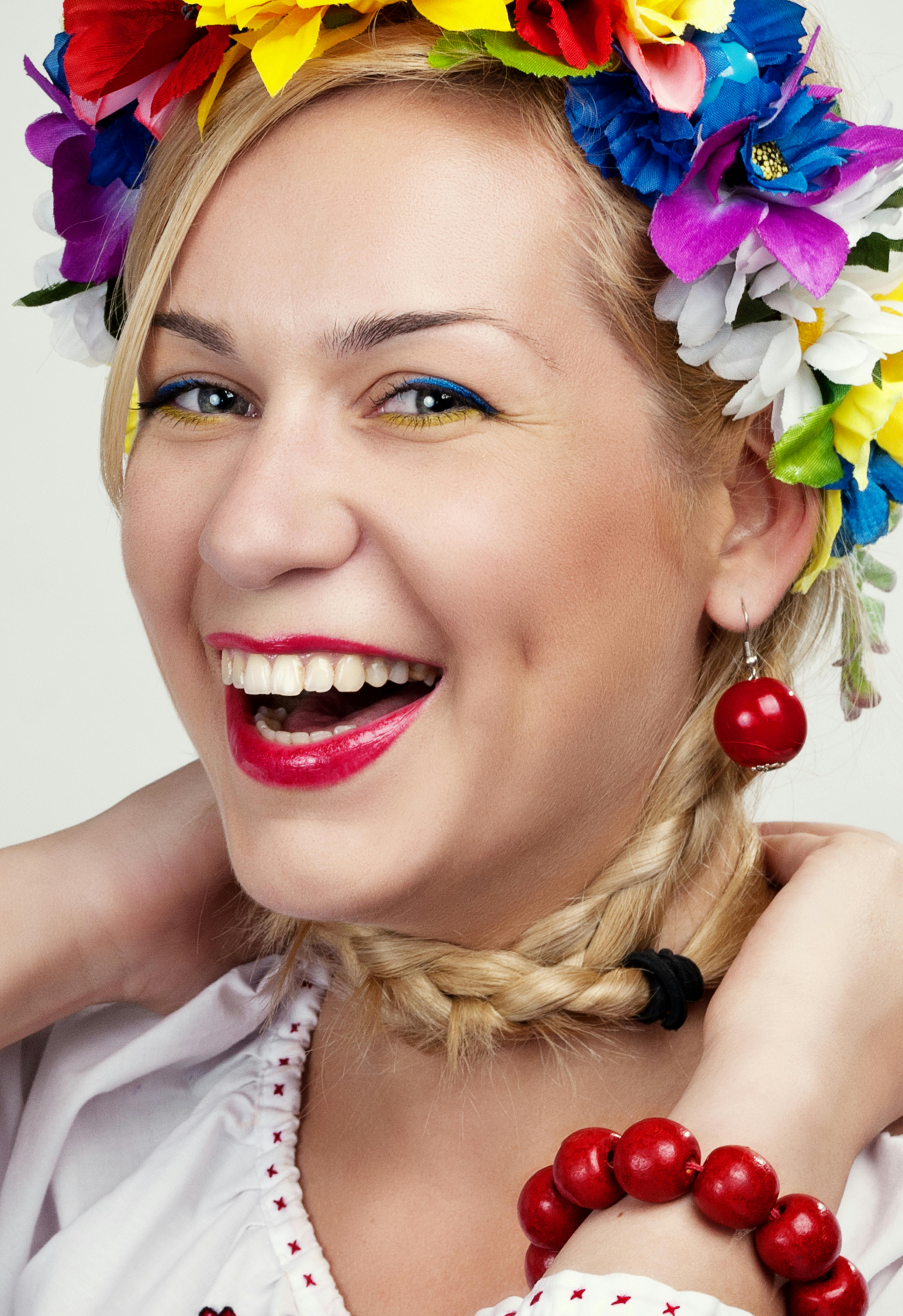 Bright portrait of a smiling woman in a traditional Ukrainian floral headpiece.
