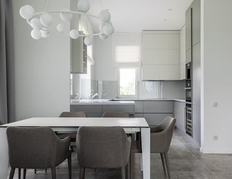 Sleek modern dining room with gray chairs, white table, and contemporary lighting.
