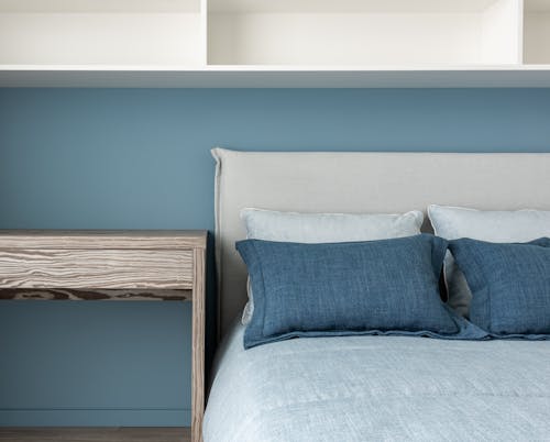 Blue soft cushions decorating bed near wooden table