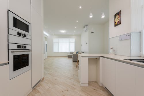 Interior of contemporary flat with clean laminate and white furniture under bright lamps