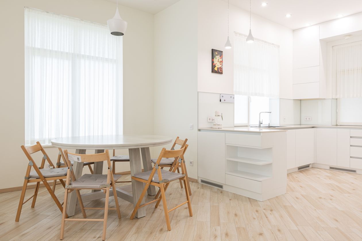 White kitchen with a round table and four wooden folding chairs with gray cushions