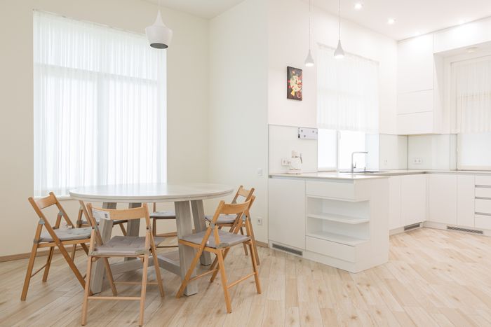 Round dining table with folding chairs in a bright white kitchen — photo by Max Vakhtbovych on Pexels