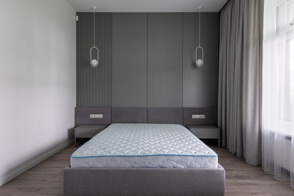 A bed with a mattress in a contemporary gray bedroom.
