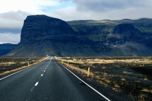 Free Open road stretching towards distant mountains under a cloudy sky. Adventure awaits. Stock Photo