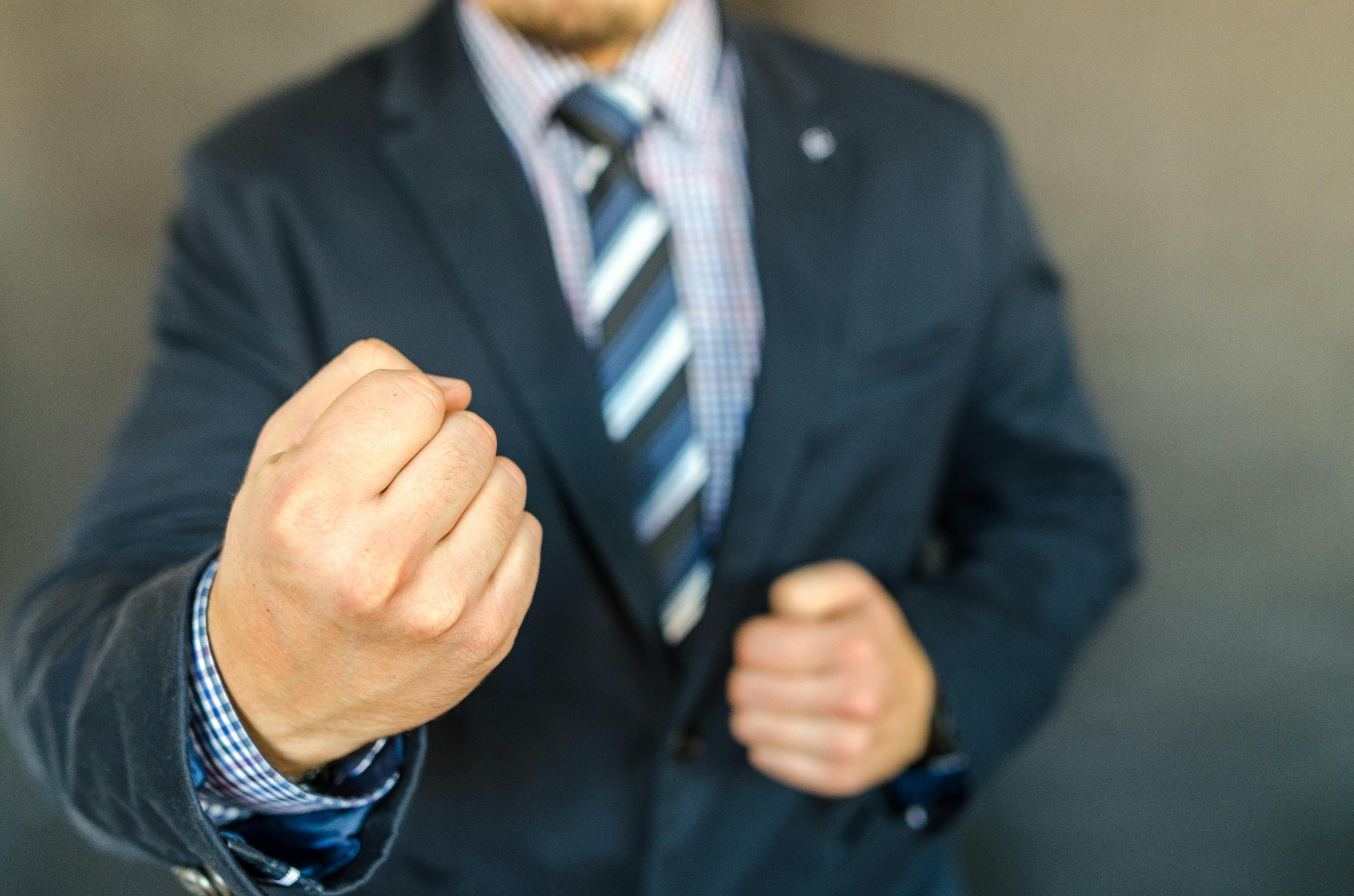 Close-up of a businessman in a suit showing determination with a fist.