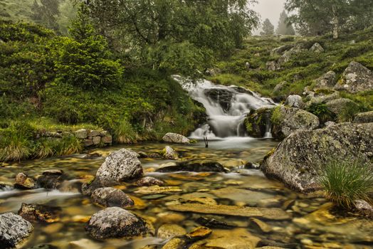 Serene stream flowing over rocks in lush French landscape.