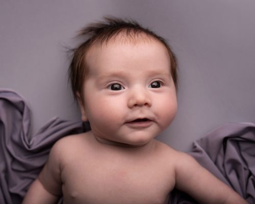 Free Close-up portrait of a cute baby with a soft blanket background. Stock Photo