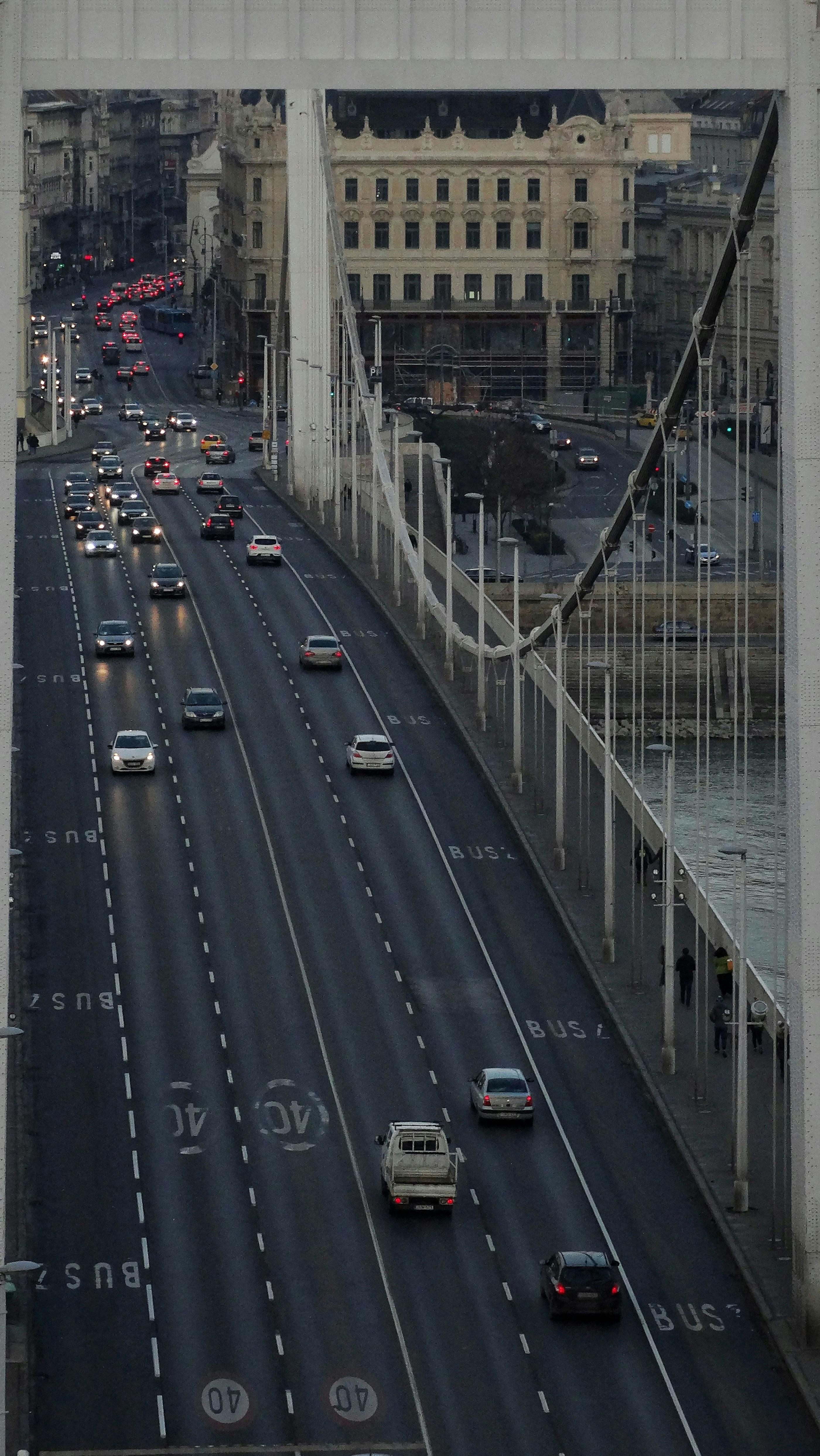 High-angle view of vehicles on a busy suspension bridge during evening rush hour in a city.