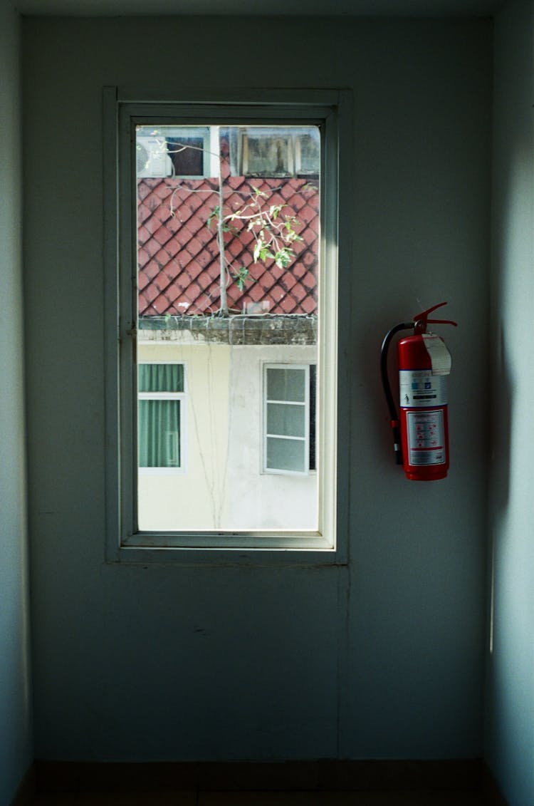 A Fire Extinguisher Hanging Near A Window