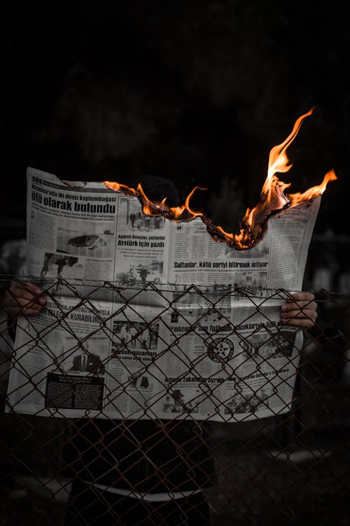 Free A Person Holding a Burning Newspaper  Stock Photo
