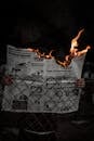 A Person Holding a Burning Newspaper
