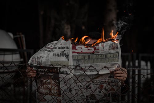 Free A Person Holding a Newspaper in Flames  Stock Photo