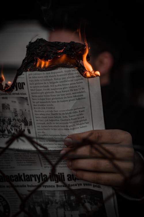 Free Close-Up of a Person Holding a Burning Newspaper  Stock Photo