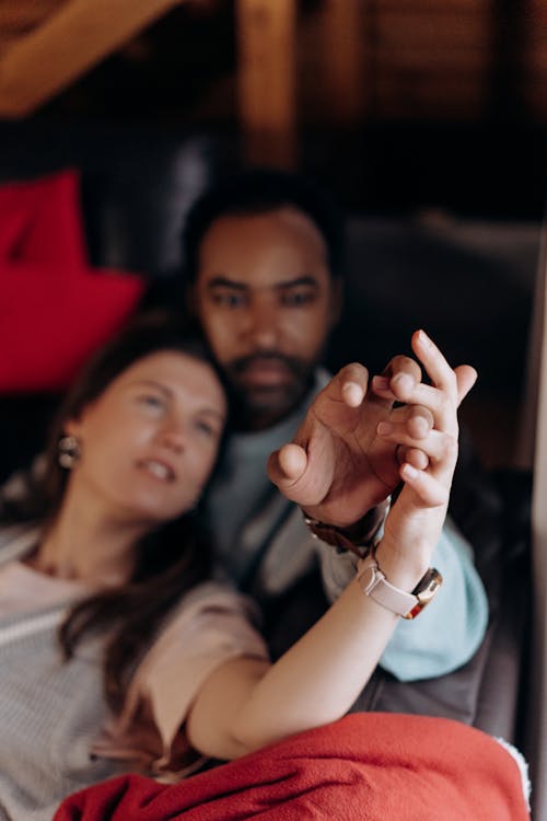 Free A Couple Holding Hands while Lying on a Sofa Stock Photo