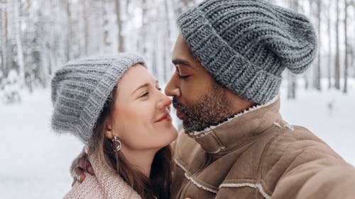 Romantic young diverse couple hugging in snowy forest on winter day